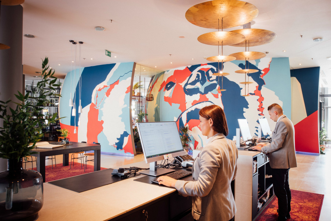 Strefa lobby w Vienna House Andel’s Cracow z wyrazistym graffiti i stołem coworkingowym zachęca do odpoczynku i urzeka stylem, fot. Vienna House Vienna House inwestuje w Polsce. Zmienia design hoteli